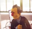 Custom puppet of a middle aged executive with prominent eyebrows, wearing a jacket.