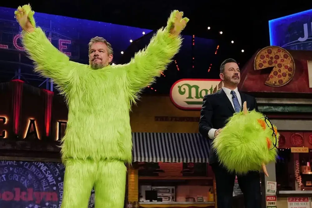 Jimmy Kimmel, removing a mascot costume head from Matt Damon