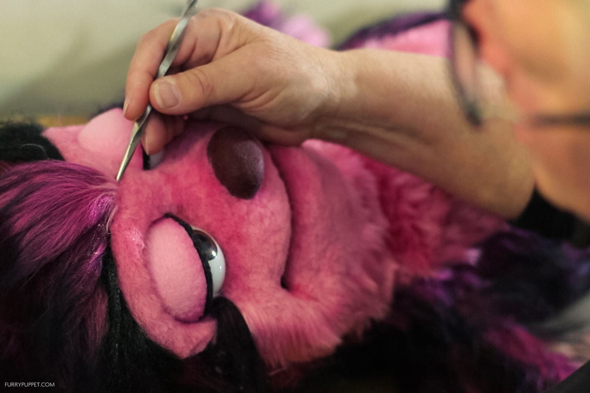 Puppet maker touching up a puppet with mechanical eyelids
